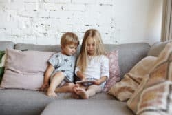 two kids sitting on clean grey couch with ipad in Wollongong